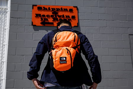 man standing in front of orange and black signage thumbnail