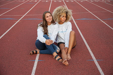two women sitting on track and field track thumbnail