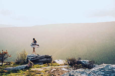 woman standing on cliff during daytime thumbnail