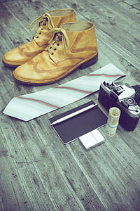 brown leather boots beside necktie and film camera on grey wooden surface thumbnail