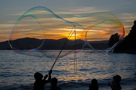 silhouette of man making large bubbles during sunset thumbnail
