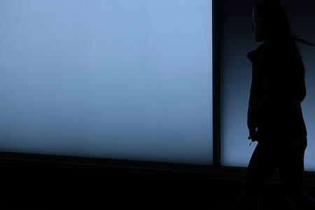 woman walking on dark area with hands in jacket thumbnail
