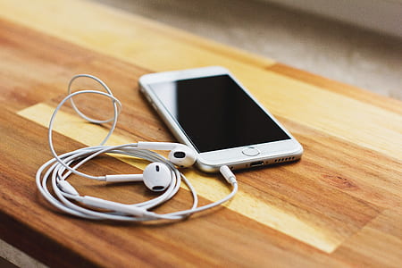 silver iPhone 6 and Apple EarPods on chair thumbnail