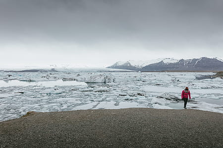 person in pink jacket walking near snow thumbnail