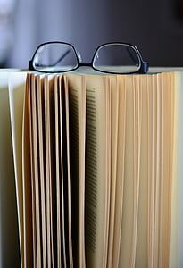 selective focus photography of opened book with eyeglasses on top of it thumbnail