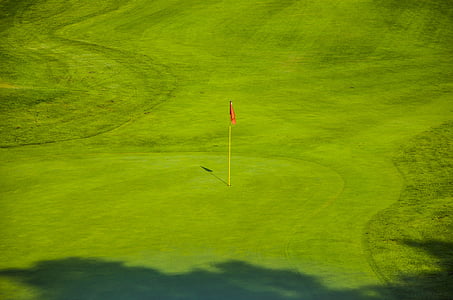 red flag on green golf course during day thumbnail