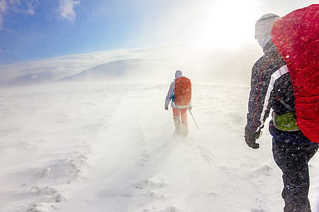 two persons hiking on snow covered hilltop during daytime thumbnail