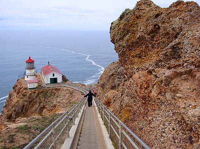 person walking down on stairs toward lighthouse thumbnail