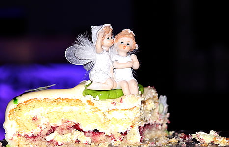 two white angel plastic toy on top of sliced cake thumbnail