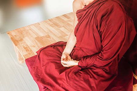 man in kasaya sitting on brown wooden surface thumbnail