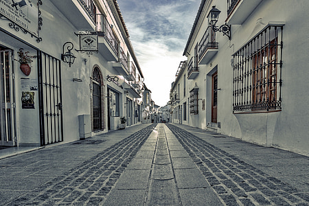 gray concrete road between white houses thumbnail