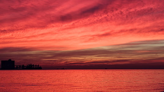 landscape photography of body of water under pink sky thumbnail