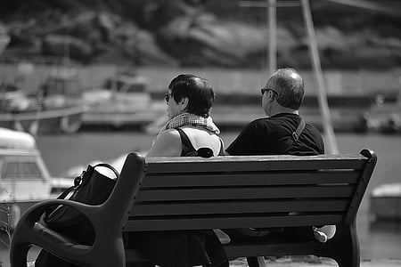 grayscale photo of couple sitting on bench thumbnail