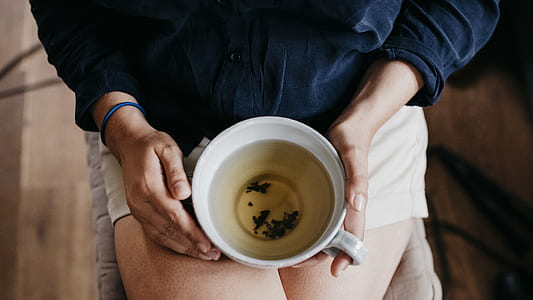 person holding white mug filled with liquid thumbnail