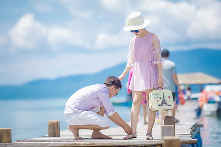 woman standing on brown dock near man wearing purple dress shirt at daytime thumbnail