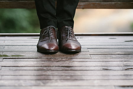 person wearing brown leather shoes standing on brown surface thumbnail