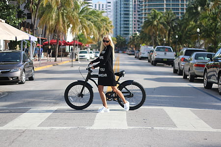Woman In Black Long Sleeve Shirt Holding Bicycle thumbnail