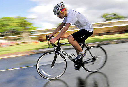 man wearing white t-shirt and black shorts on bike in time laps photography thumbnail