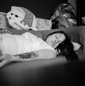 woman wearing white cap-sleeved shirt sleeping on sofa thumbnail