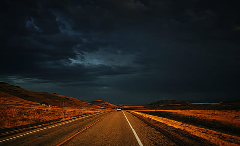vehicle on gray concrete road under black sky thumbnail