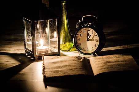 candle lantern and round white and black clock on top of table thumbnail