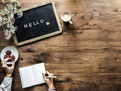 Flat Lay Photography of Person Holding Cookie and Pen Near Hello Board thumbnail