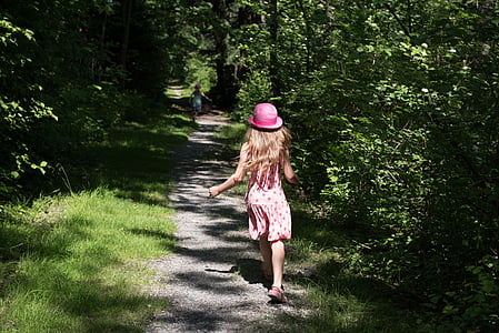 girl wearing pink hat running through forest thumbnail