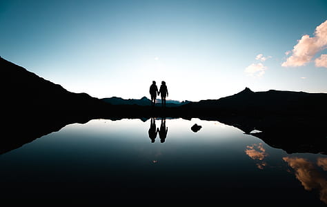 silhouette photography of couple holding hands near body of water thumbnail