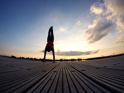 person on orange shirt doing hand stand on brown pavement thumbnail