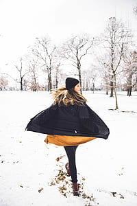 woman walking on snow field under white sky thumbnail