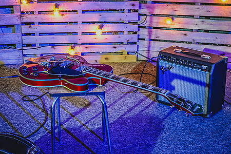red Gretsch electric guitar on top of stool beside Fender amplifier thumbnail