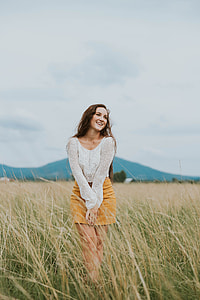 woman in white sheer scoop-neck long-sleeved shirt and brown miniskirt walking on rice fields during daytime thumbnail