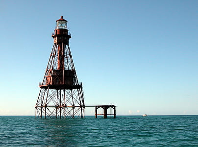 red lighthouse in middle on body of water thumbnail