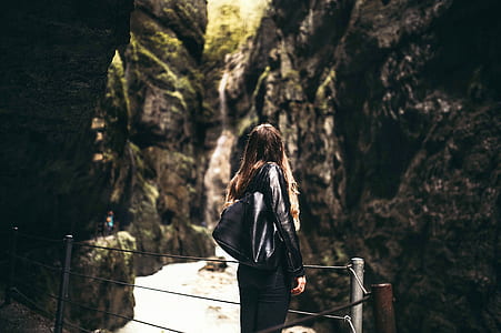 Woman in Black Leather Jacket Standing in Front of Gray Fence thumbnail