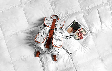 white and brown leather bucket backpack beside cookbook thumbnail