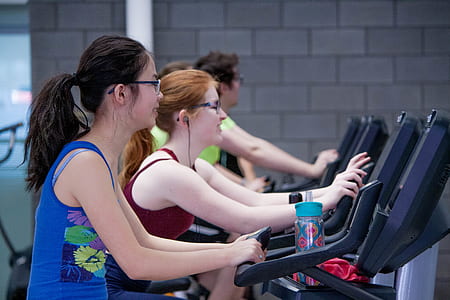 two women on black stationary bikes in gym thumbnail