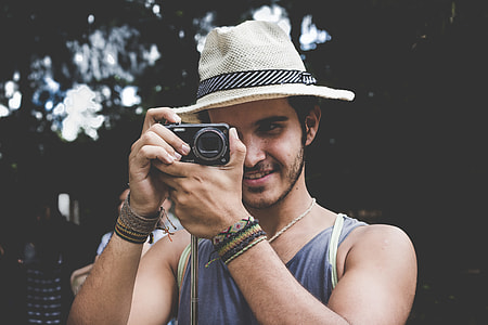 man in brown fedora hat taking photo thumbnail