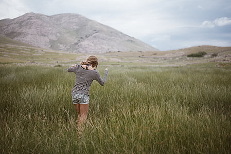 woman walking on green grass field during daytime thumbnail