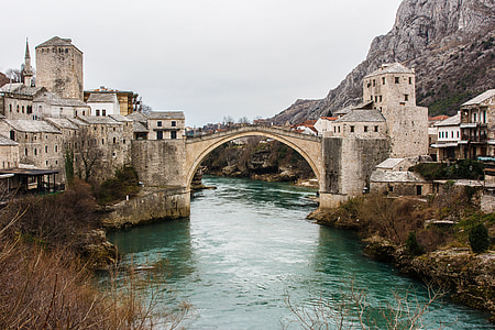 bridge between concrete buildings above body of water thumbnail