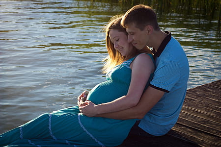 man and woman sitting on brown wooden dock thumbnail