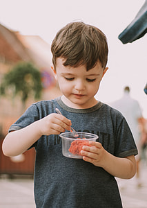boy wearing gray tee shirt holding clear glass container with food inside thumbnail