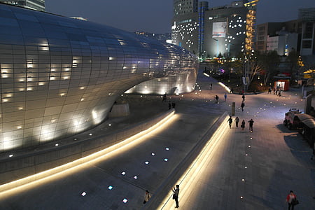 people walk through near white concrete building at night time thumbnail