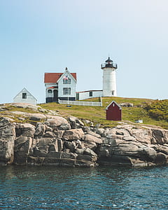 2-storey house and lighthouse on island near body of water thumbnail