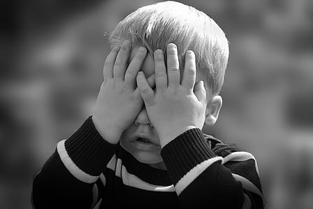 grayscale photo of boy covering his face weawring black and white striped sweatshirt thumbnail