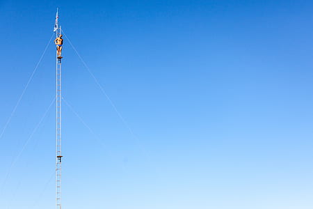 topless man standing on tower under blue and white sky thumbnail