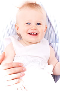 baby wearing white tank dress leaning on person thumbnail