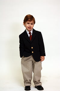 boy in suit jacket standing near white wall thumbnail
