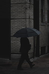 man holding umbrella near wall thumbnail