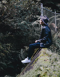 man sitting on rock beside fence thumbnail