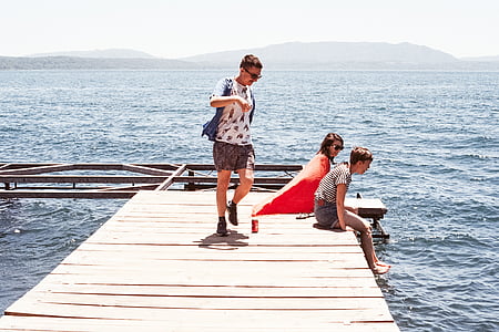 woman and two men sitting on sea dock thumbnail
